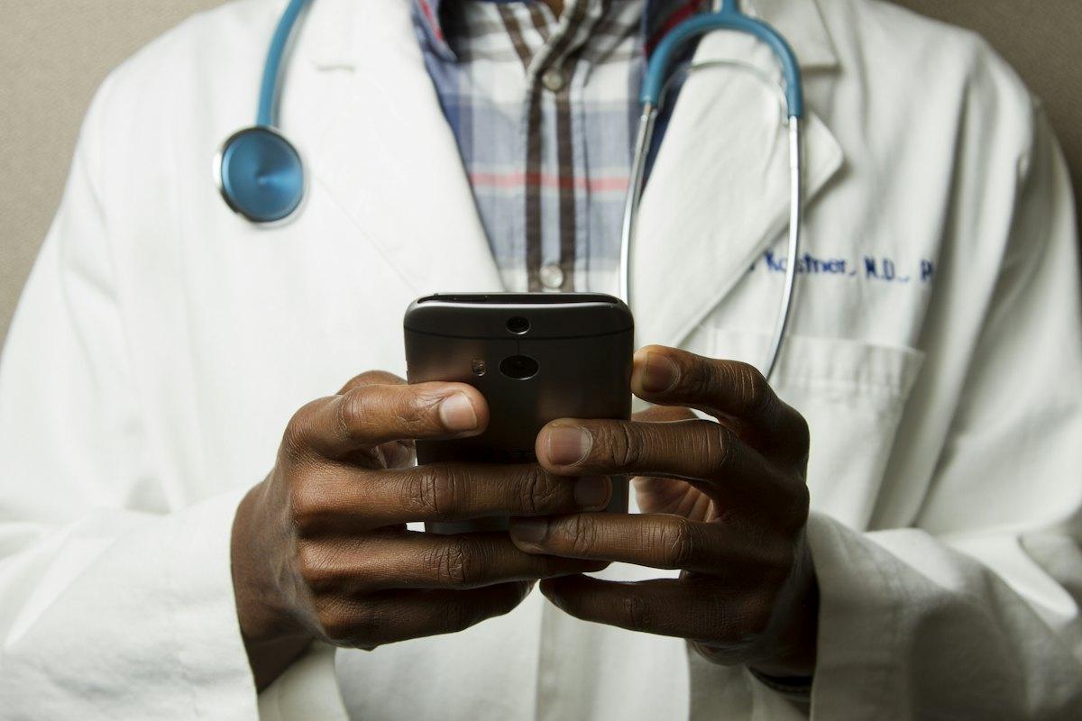 Médico com estetoscópio utilizando celular, demonstração