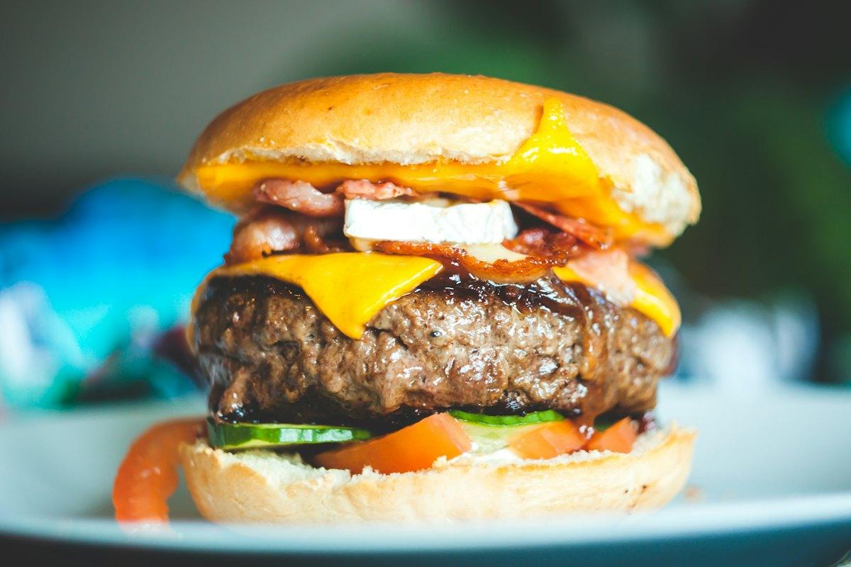 Hambúrguer artesanal com cheddar e bacon em destaque, demonstração